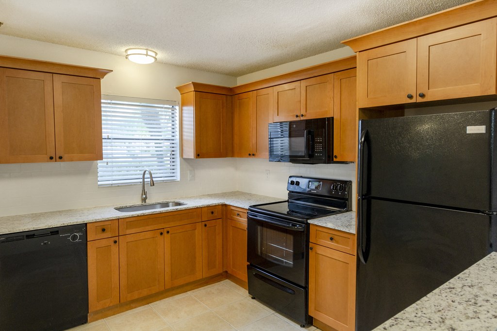 A kitchen with black appliances and wooden cabinets.